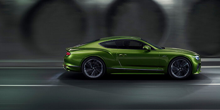  Bentley Edinburgh Bentley Continental GT coupe in Tourmaline Green paint driving in profile on a dark road