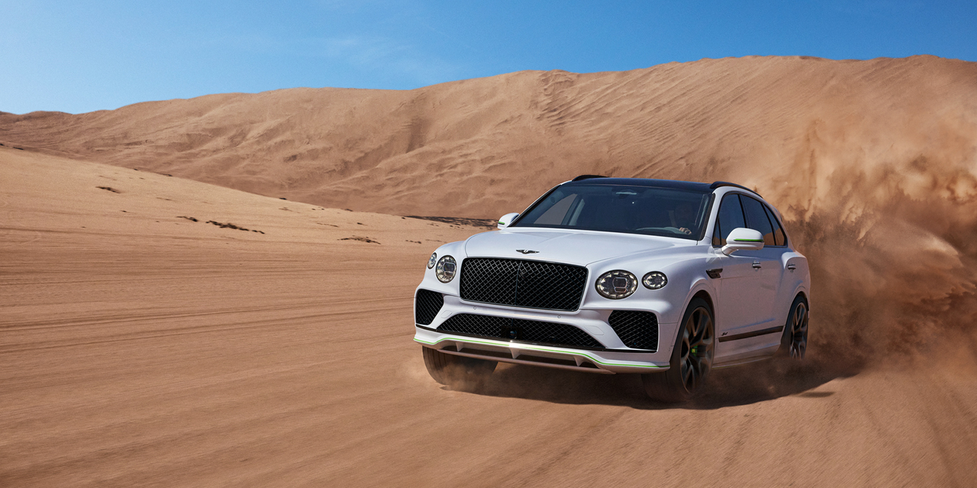 Bentley Edinburgh Bentley Bentayga Speed SUV front three quarter in Snow Quarts Pearlescent by Mulliner white paint driving dynamically through the desert