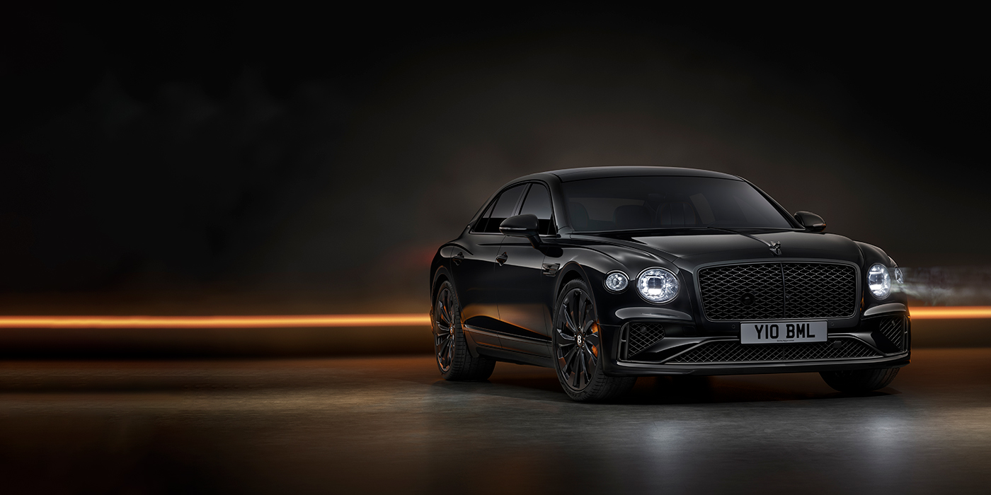 Bentley Edinburgh Bentley Flying Spur Black Edition sedan in Black Crystal paint against a dark grey and copper coloured background