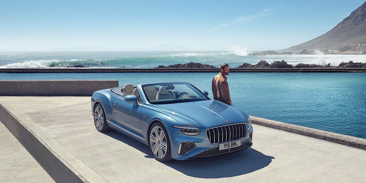 Bentley Edinburgh New Bentley Continental GTC Azure convertible front view in Light Windsor blue paint with 22 inch ten spoke wheels parked by the sea in the sunshine