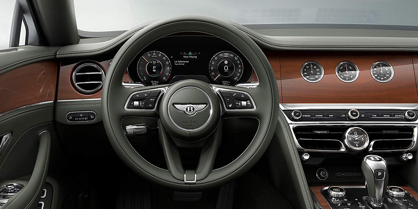 Bentley Edinburgh New Bentley Flying Spur sedan front cabin in Cumbrian Green hide and Crown Cut walnut veneer showing steering wheel and Rotating Display with three clocks on face