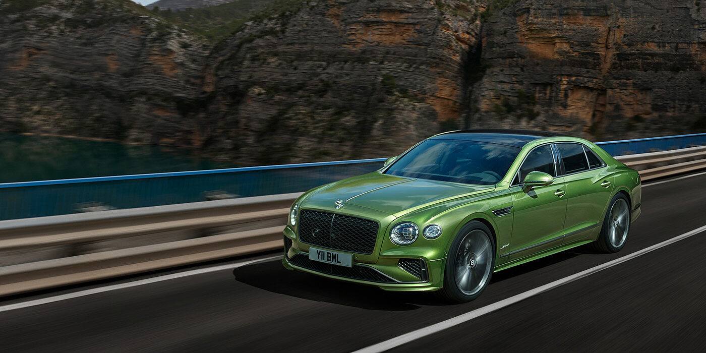 Bentley Edinburgh Bentley New Flying Spur Speed v8 hybrid sedan driving dynamically on a mountain road in Tourmaline Green paint