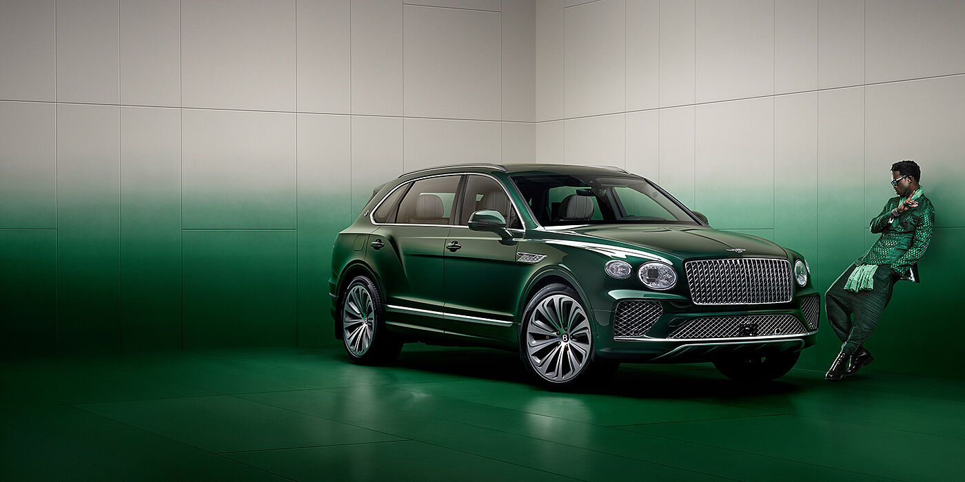 Bentley Edinburgh Wisdom K leans against wall next to Bentley Bentayga Extended Wheelbase Atelier Edition SUV in Light Emerald green paint