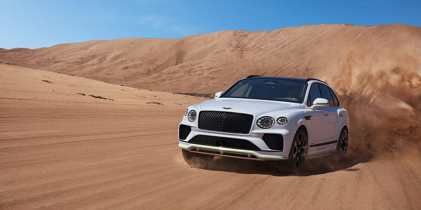 Bentley Edinburgh Bentley Bentayga Speed SUV front three quarter in Snow Quarts Pearlescent by Mulliner white paint driving dynamically through the desert