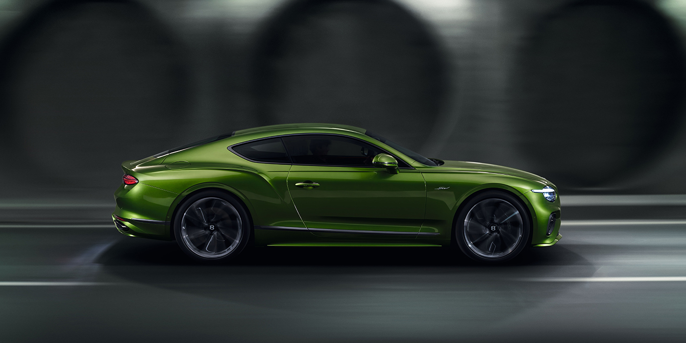 Bentley Edinburgh Bentley Continental GT coupe in Tourmaline Green paint driving in profile on a dark road