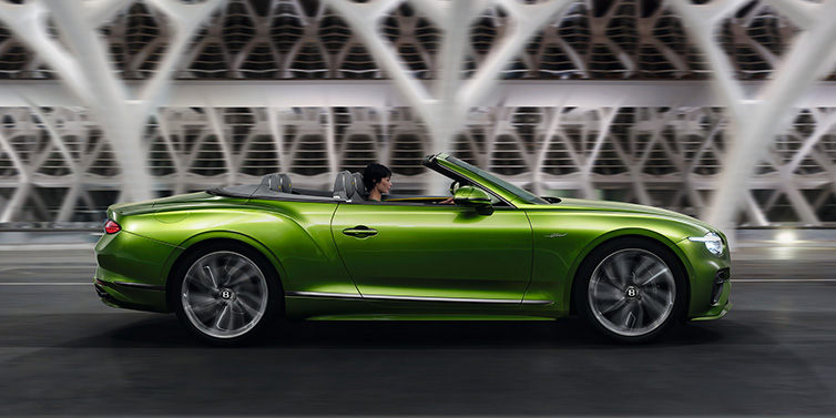 Bentley Edinburgh Bentley Continental GTC Speed convertible side profile in Tourmaline Green paint driving dynamically on a bridge at night