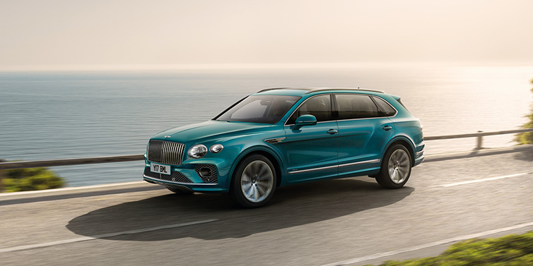 Bentley Edinburgh Bentley Bentayga Extended Wheelbase Azure SUV in Topaz blue paint driving dynamically by the ocean