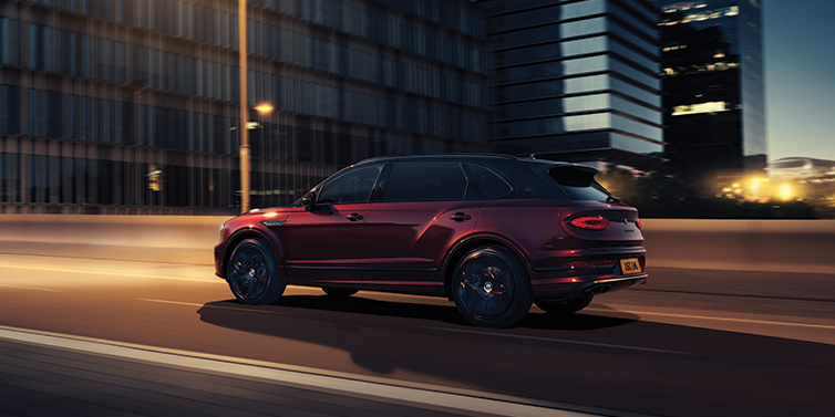 Bentley Edinburgh Bentley Bentayga Extended Wheelbase Mulliner SUV in Cricket Ball red paint driving dynamically in city at night