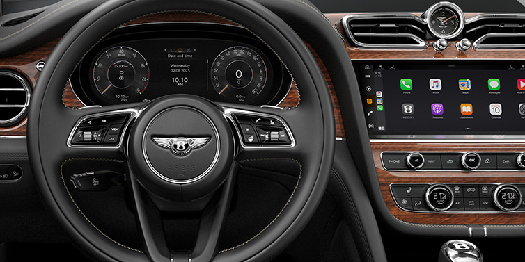 Bentley Edinburgh Bentley Bentayga SUV front interior detail of steering wheel and driver screens surrounded by Beluga black hide and Crown Cut Walnut veneer